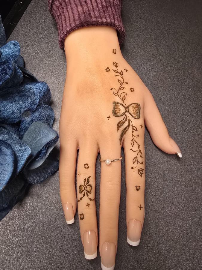 Minimal bow mehndi design with tiny bows and leafy vines